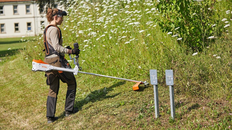 Gardener using tool to strim grass banks